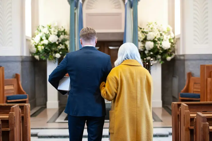 Church aisle lined with white flower arrangements at a memorial service