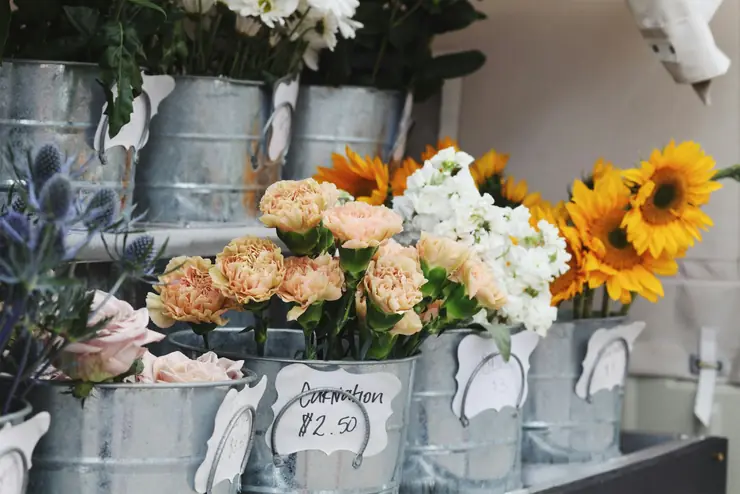 Florist buckets of sunflowers, roses and mixed stems with a handwritten price tag