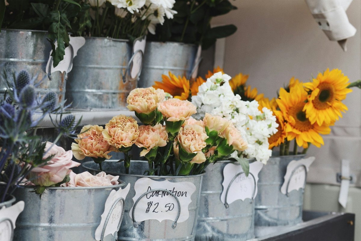Florist buckets of sunflowers, roses and mixed stems with a handwritten price tag