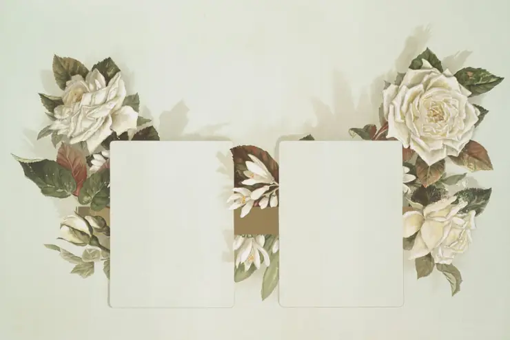 Two blank cards laid on a table surrounded by white and cream flowers