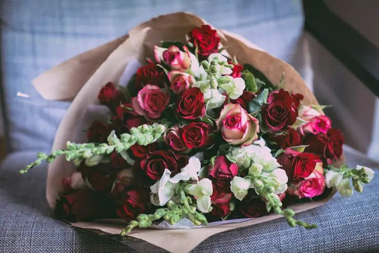 Bouquet of red roses and white flowers wrapped in kraft paper