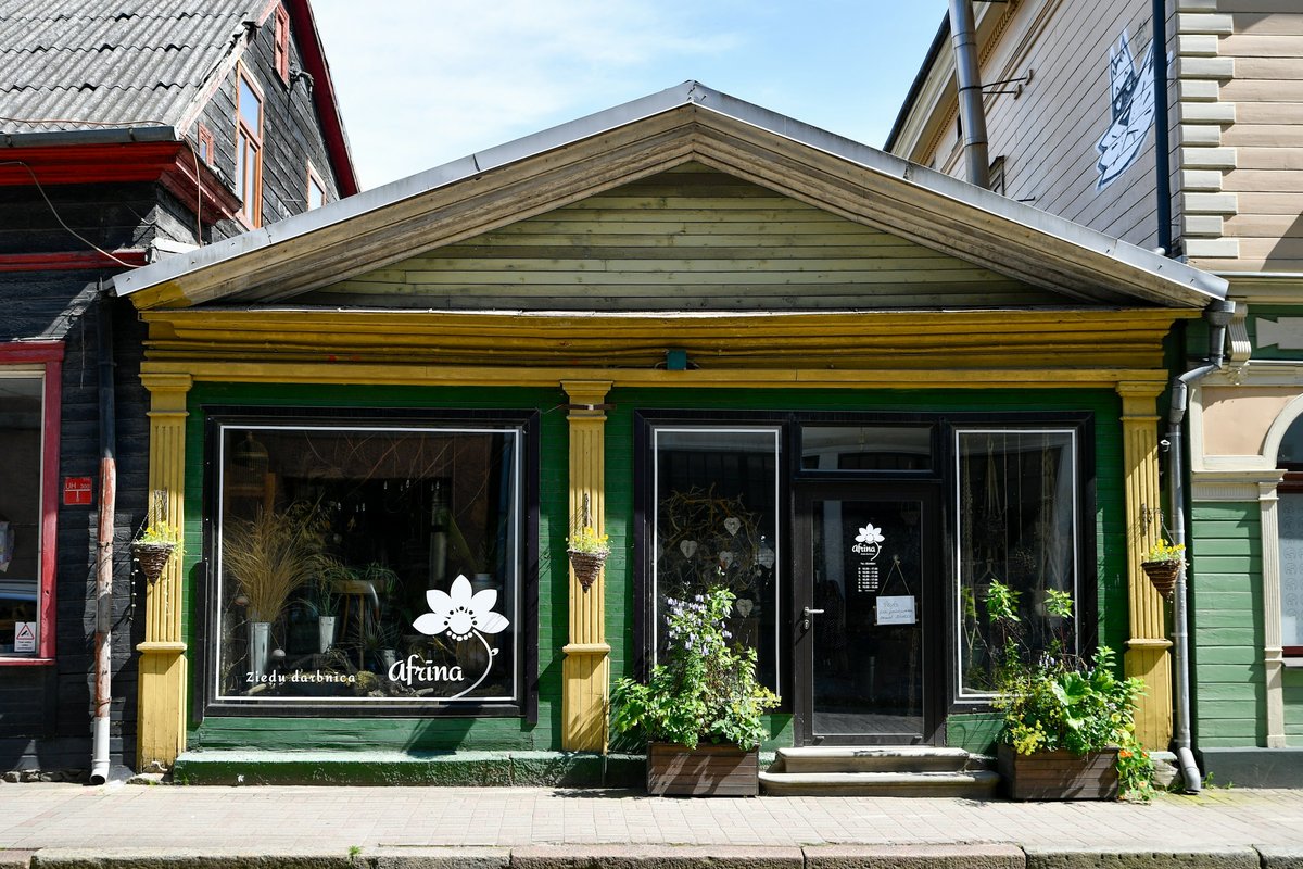 A small flower shop storefront with plants and flowers outside the door