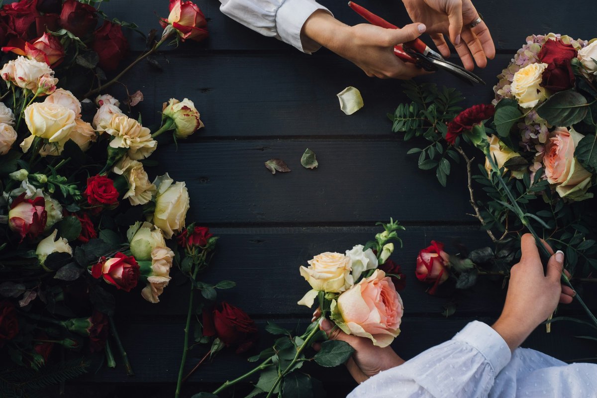 A florist's hands building a bouquet of roses on a dark work table
